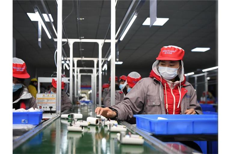 Menschen arbeiten in einer Fabrik am Fließband. Bei dem neuen Gesetz geht es auch um die Vermeidung von Ausbeutung und Kinderarbeit in weltweiten Lieferketten. Foto: Xue Yuge/XinHua/dpa
