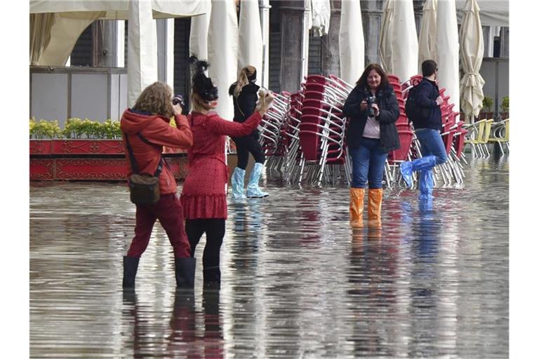 Menschen auf dem überfluteten Markusplatz in Venedig. Foto: Matteo Tagliapietra/LaPresse/dpa