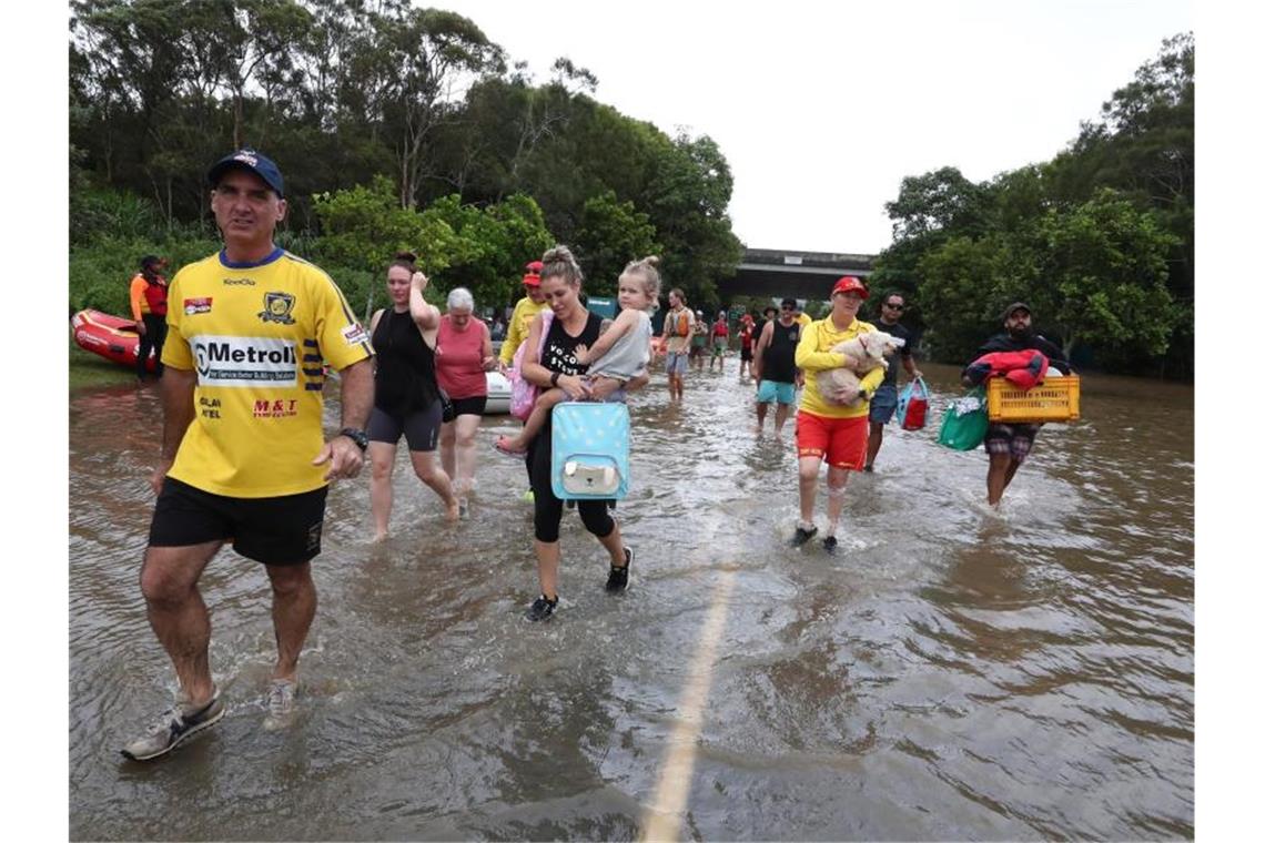 Historische Überschwemmungen in Australien Menschen auf einer überschwemmten Straße im australischen Chinderah. Foto: Jason O’brien/AAP/dpa