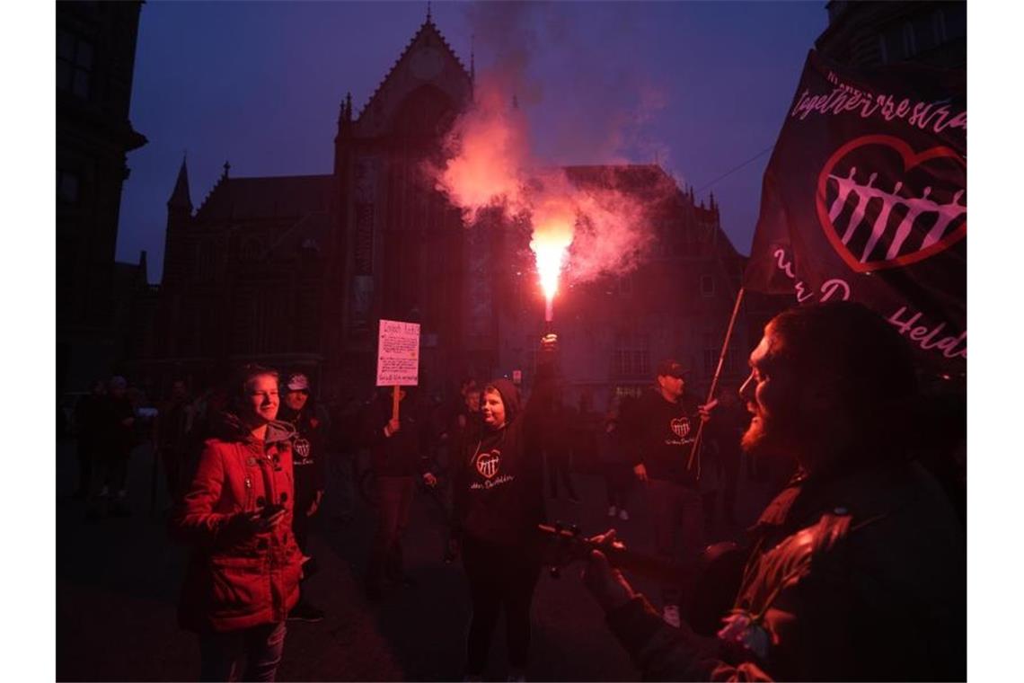 Menschen bei einer Demonstration gegen die Covid-19-Beschränkungen in Amsterdam teil. Nach den heftigen Ausschreitungen in Rotterdam haben Randalierer in verschiedenen Städten der Niederlande für Unruhen gesorgt. Foto: Peter Dejong/AP/dpa