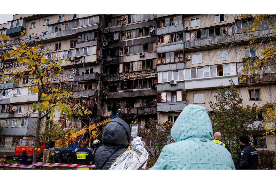 Menschen beobachten die Arbeit der Feuerwehr in einem zerstörten Wohnhaus nach einem russischen Drohnenangriff.