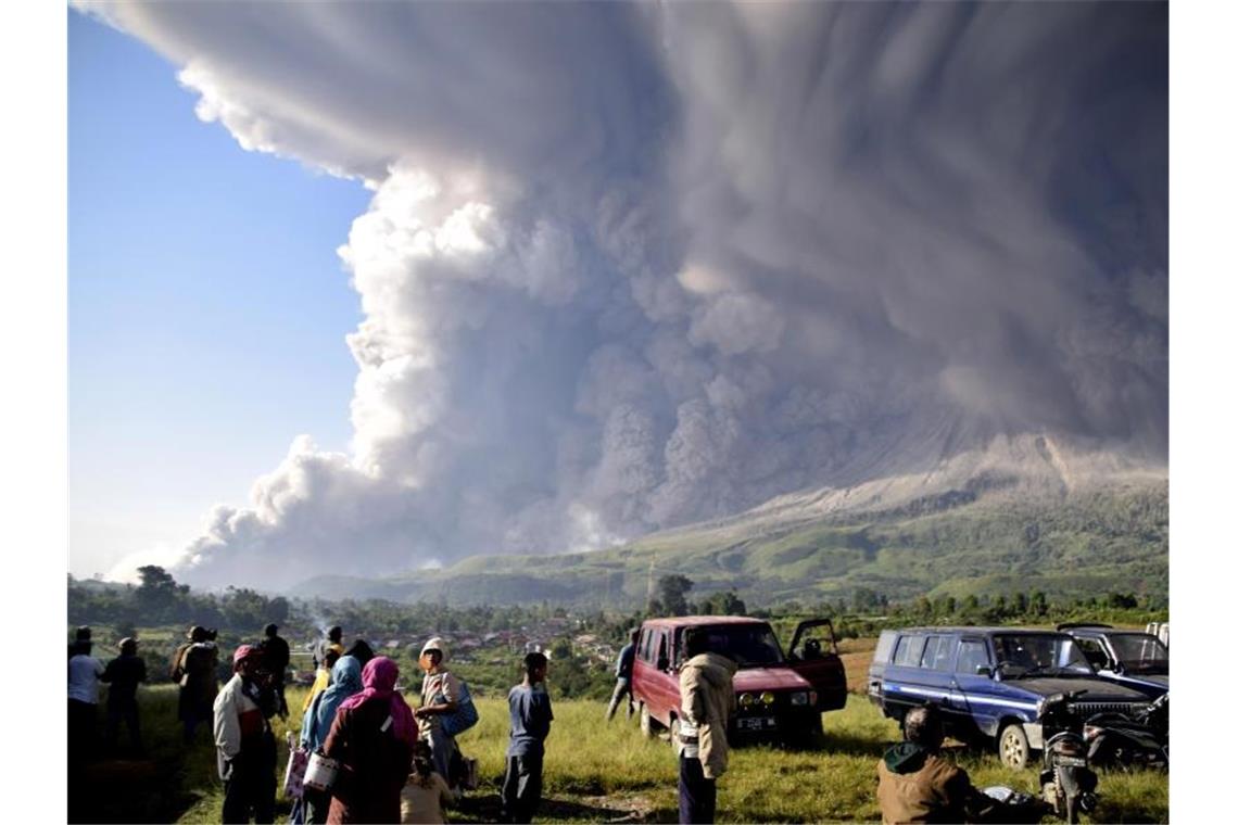 Menschen beobachten eine Eruption des Vulkans Sinabung. Foto: Uncredited/AP/dpa