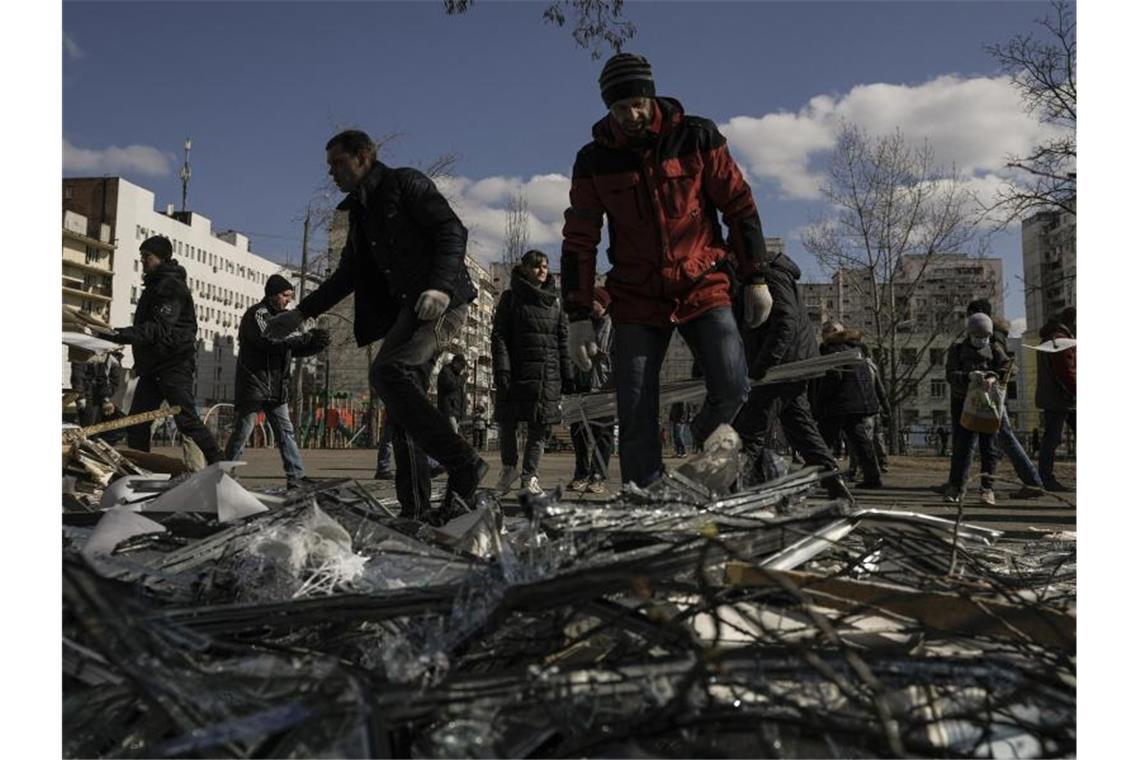 Krieg in der Ukraine: Das ist die aktuelle Lage Menschen beseitigen in Kiew Trümmer nachdem Teile einer russischen Rakete auf einem Wohnblock gelandet sind. Foto: Vadim Ghirda/AP/dpa