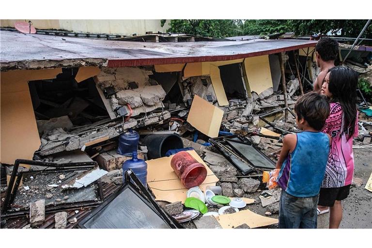 Menschen betrachten ein eingestürztes Gebäude in Bogo City, Provinz Cebu, nach einem Erdbeben am späten Dienstag.