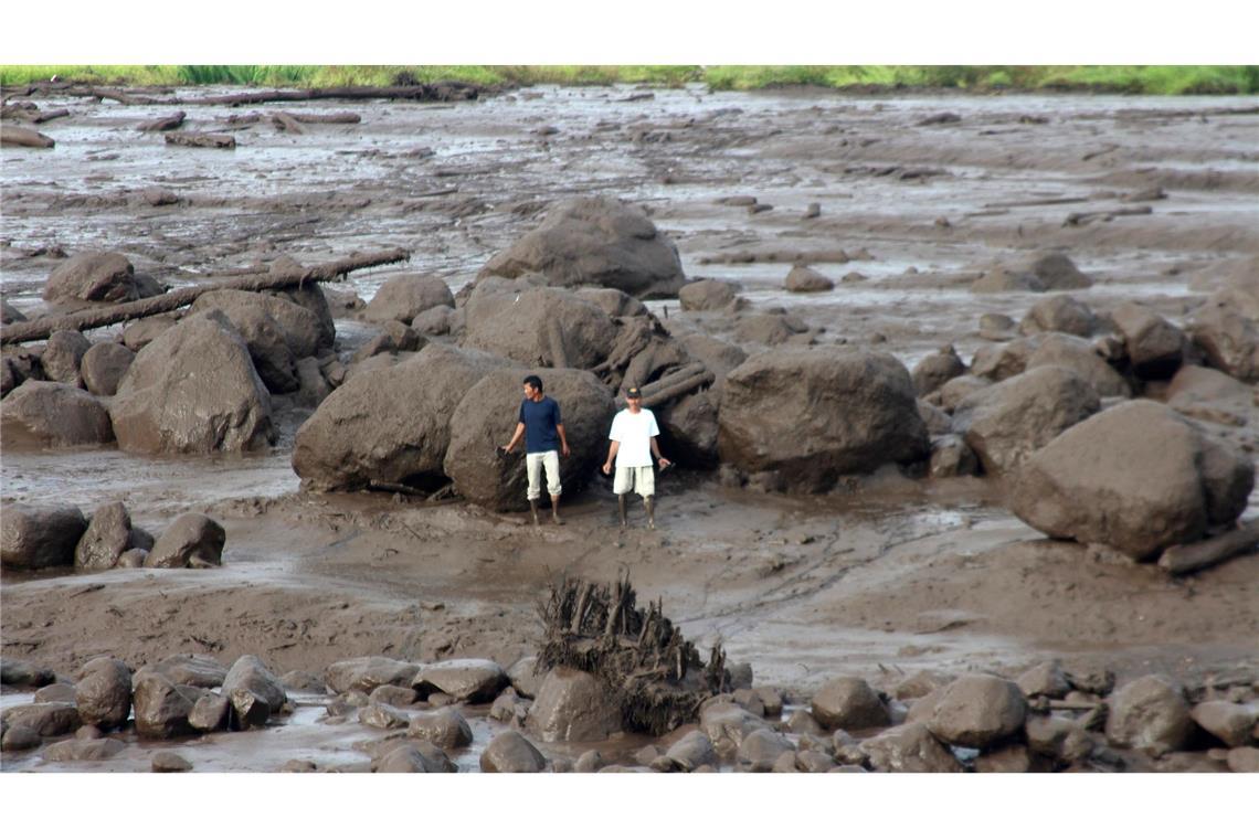 Menschen betrachten ein von einer Sturzflut betroffenes Gebiet in Indonesien. Schwere Regenfälle und Ströme kalter Lava und Schlamm  haben Sturzfluten ausgelöst. Mehr als ein Dutzend Menschen wurden dabei getötet.
