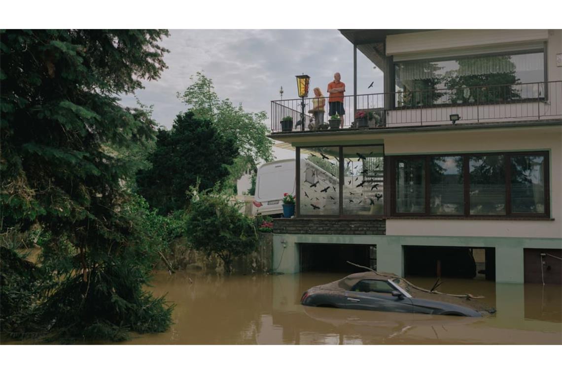 Menschen blicken von einem Balkon in Ahrweiler auf die braune Flut: ein Bild des Kollektivs Docks von der Flutkatastrophe 2021. 