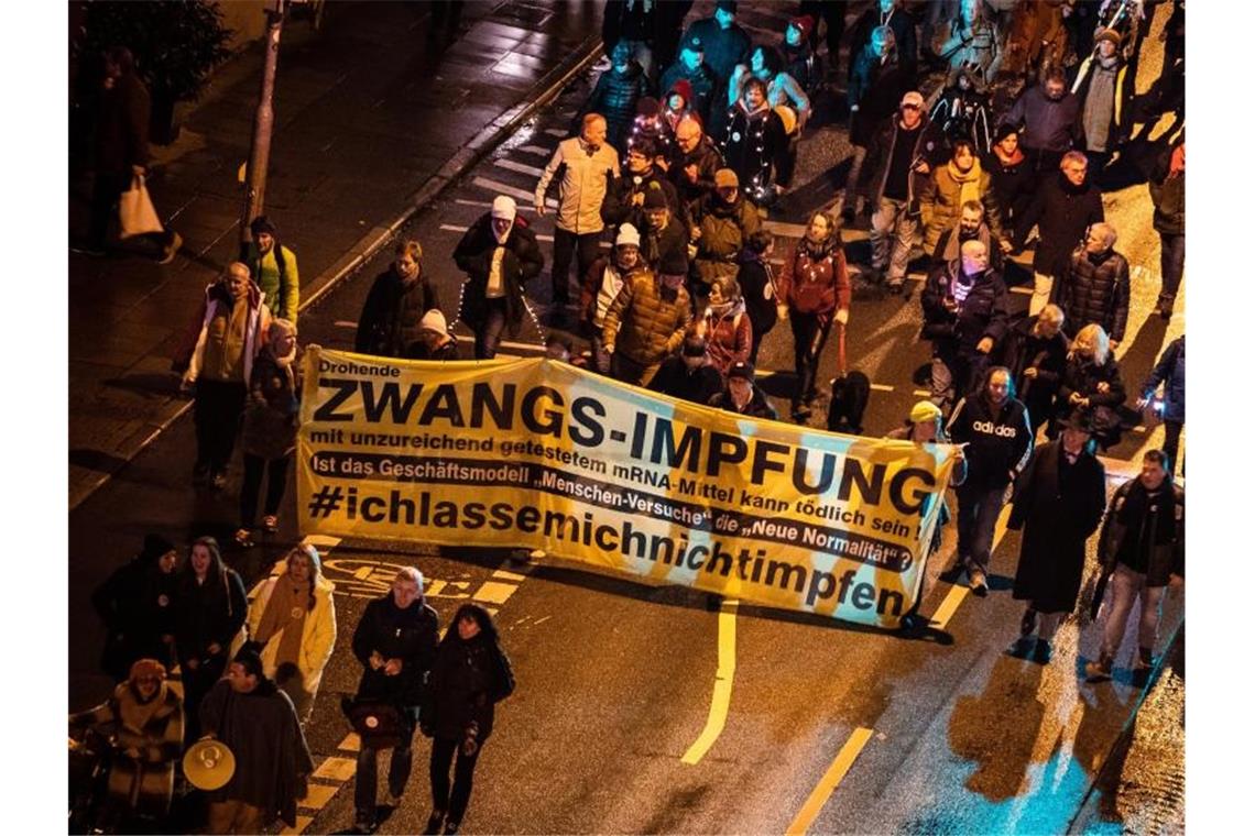 Menschen demonstrieren am Silvesterabend in Stuttgart gegen die Corona-Politik. Foto: Christoph Schmidt/dpa