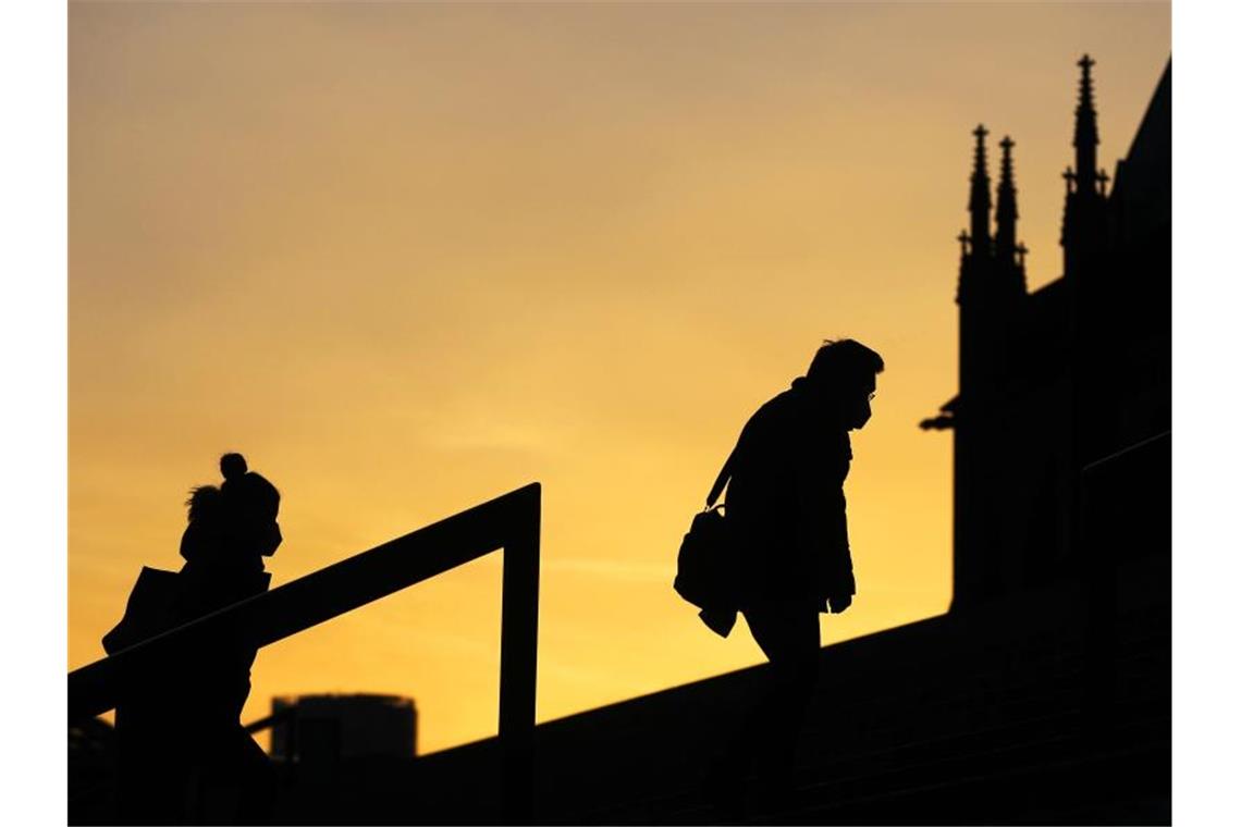 3883 Corona-Neuinfektionen und 415 neue Todesfälle Menschen, die Schutzmasken tragen, gehen im Morgenlicht eine Treppe in Köln hinauf. Die sogenannte Sieben-Tage-Inzidenz in Nordrhein-Westfalen ist aktuell auf 61,7 gestiegen. Foto: Oliver Berg/dpa