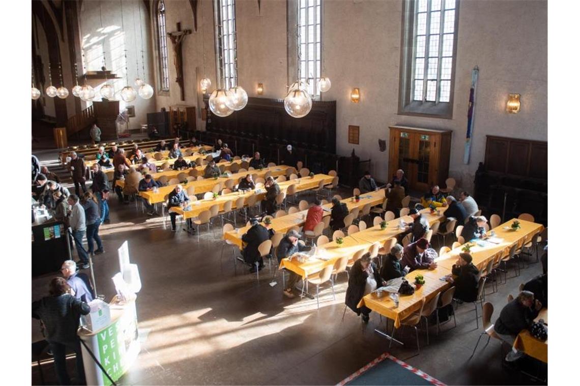 Menschen erhalten eine Mahlzeit in der Leonhardskirche. Foto: Tom Weller/dpa/Archivbild