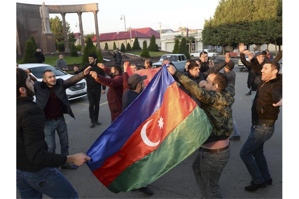 Menschen feiern in Ganja und halten aserbaidschanische Nationalflaggen. Foto: Aydin Mammedov/AP/dpa