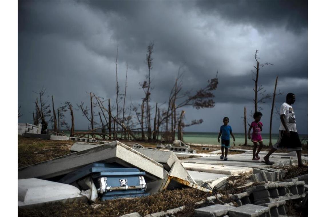 Menschen gehen an den Trümmern auf einem Friedhof auf den Bahamas vorüber. Foto: Ramon Espinosa/AP