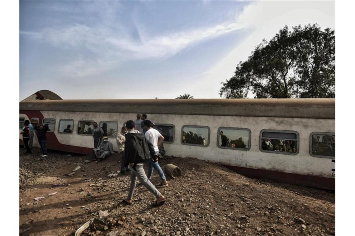 Menschen gehen an einem entgleisten Waggon in der Provinz Kaljubia vorbei. Foto: Sayed Hassan/dpa