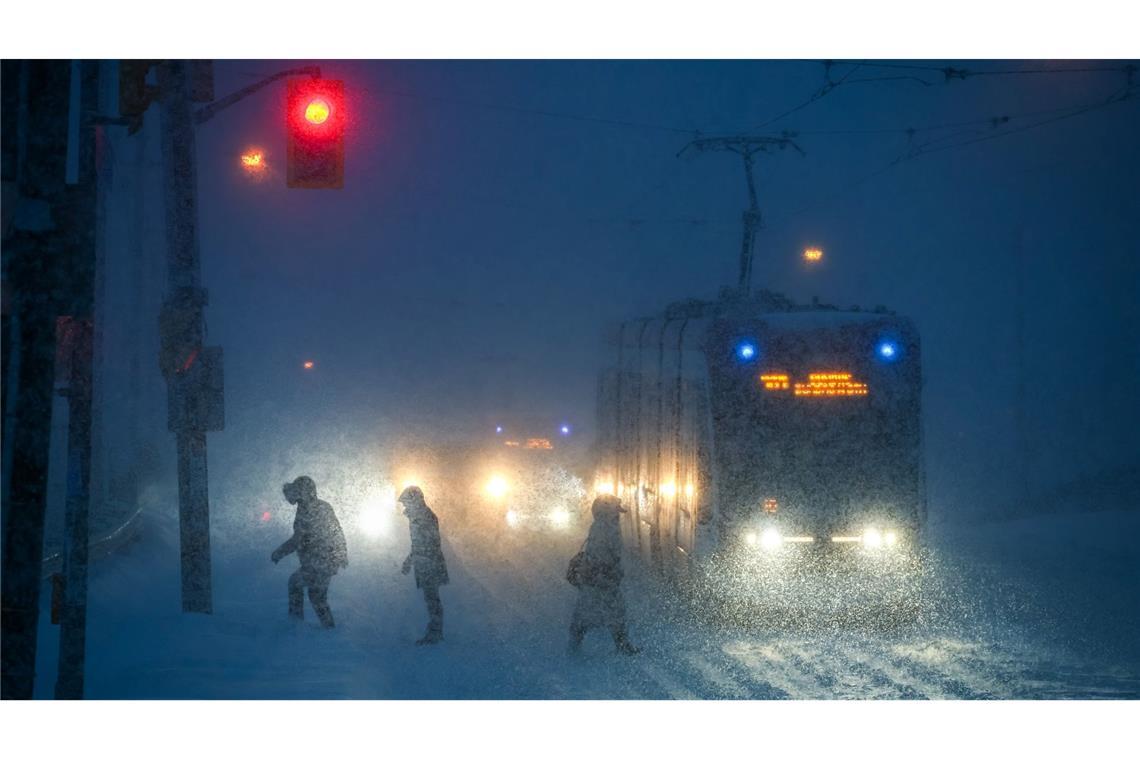 Menschen gehen bei Schneefall durch die Innenstadt von Toronto.