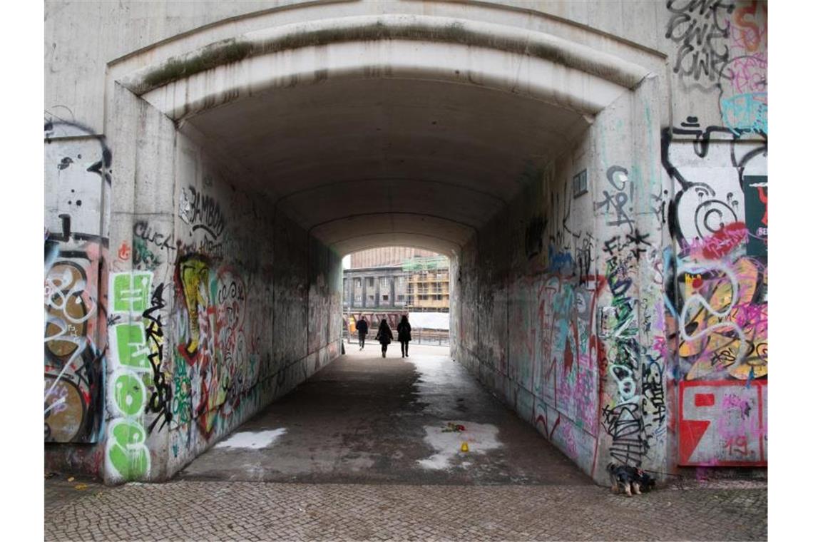 Menschen gehen durch die Unterführung zum Monbijoupark in Berlin-Mitte, in der Unbekannte eine Rose und eine Kerze abgelegt haben. Der 13-Jährige war hier bei einem Streit tödlich verletzt worden. Foto: Paul Zinken/dpa