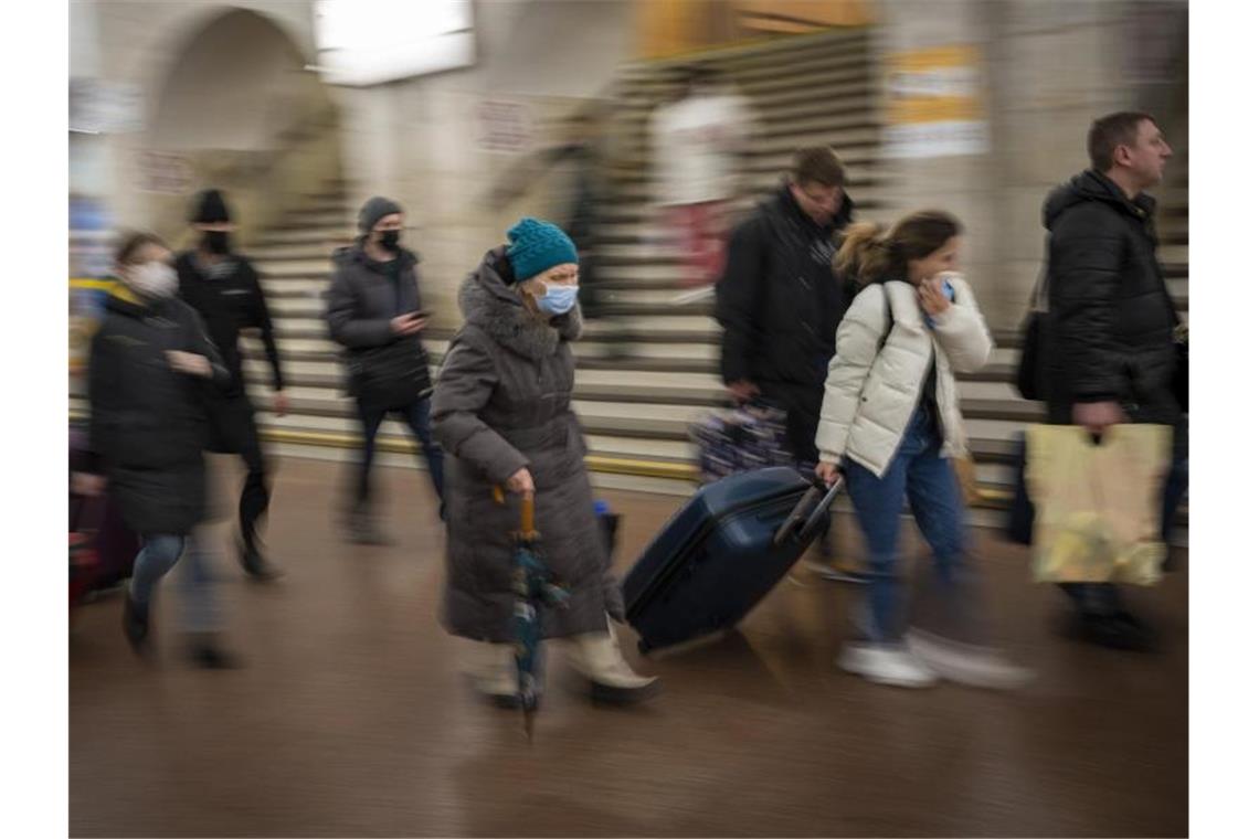 Menschen gehen in einer Bahnstation zu einem Zug, um Kiew zu verlassen. Foto: Emilio Morenatti/AP/dpa
