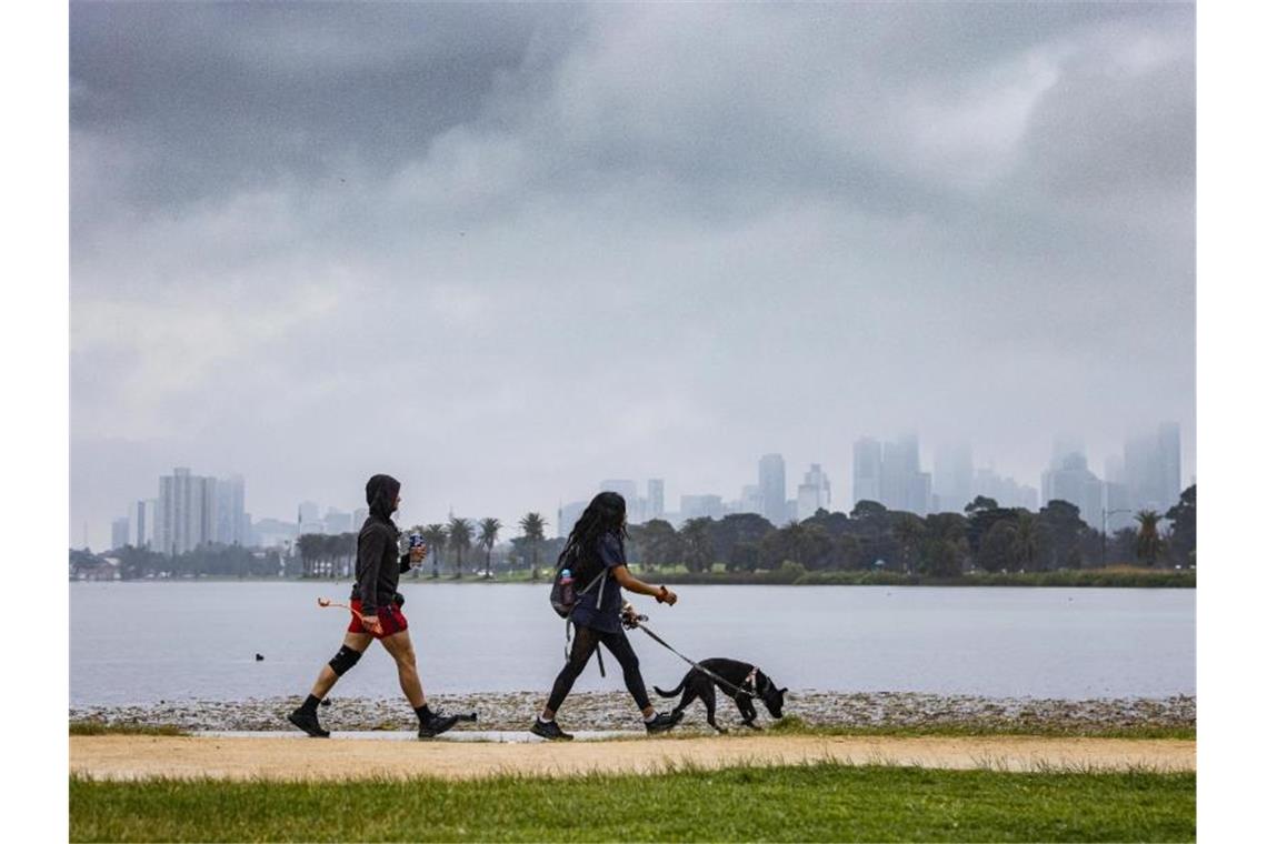 Menschen gehen mit einem Hund am Albert Park Lake in Melbourne spazieren. (Archivbild). Foto: Daniel Pockett/AAP/dpa