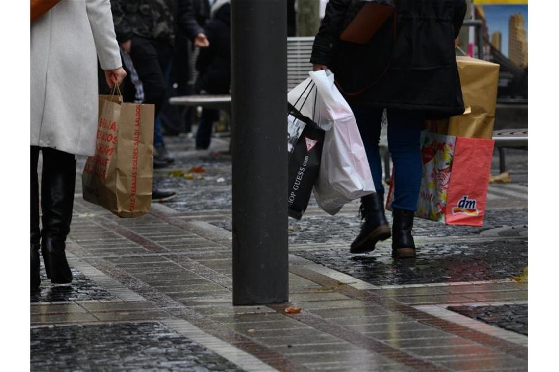 Menschen gehen mit vollen Einkaufstüten über eine Einkaufsstraße. Foto: Andreas Arnold/dpa/Archivbild