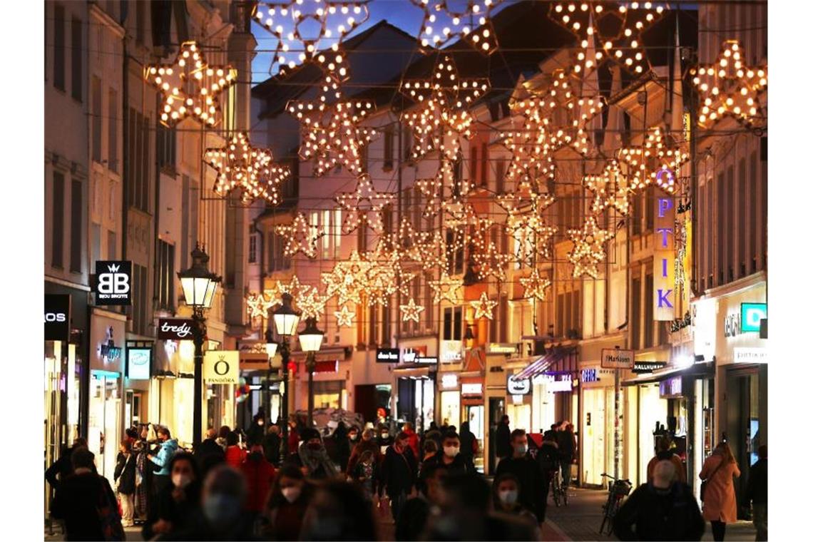 Menschen gehen unter Weihnachtsbeleuchtung durch die Fußgängerzone in Bonn. Foto: Oliver Berg/dpa