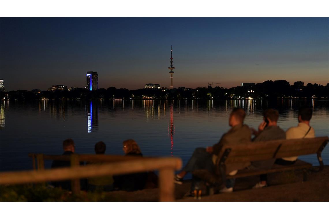 Menschen genießen die Abendstimmung am Ufer der Außenalster in Hamburg.