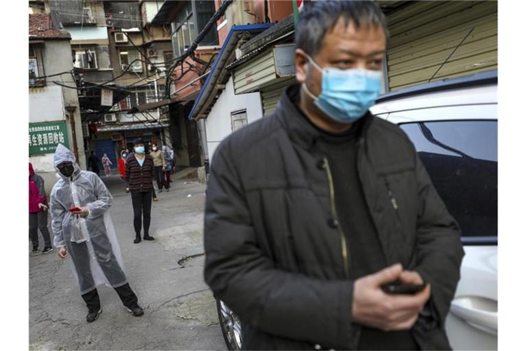 Menschen halten Abstand, während sie in Wuhan für Schweinefleisch anstehen. Foto: Uncredited/CHINATOPIX/dpa