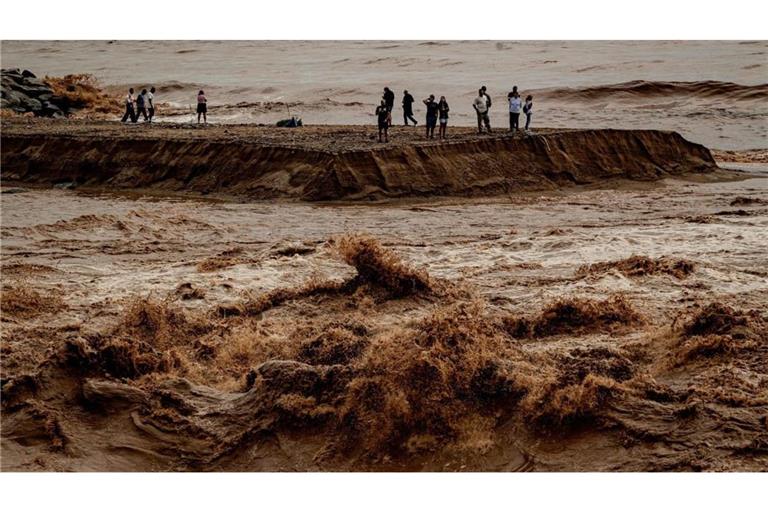 Menschen halten sich an der Mündung des Flusses Besòs nördlich von Barcelona auf, der nach einer Nacht mit sintflutartigen Regenfällen in ganz Katalonien angeschwollen und mit Sedimenten beladen ist.