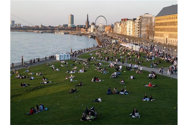 Menschen halten sich an der Rheinuferpromenade und den Rheinwiesen in Düsseldorf auf. Laut dem RKI breitet sich die sehr ansteckende Corona-Variante B.1.1.7 rasch in Deutschland aus. Foto: Jonas Güttler/dpa