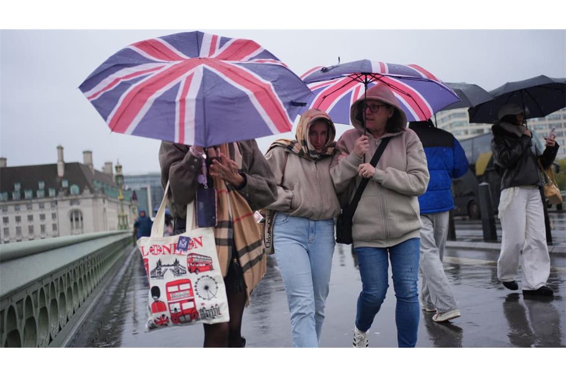 Menschen im Regen auf der Westminster Bridge in London.