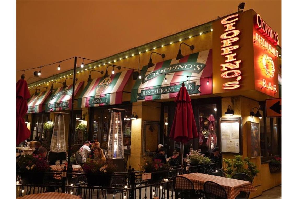 Menschen in San Francisco sitzen unter einem orange gefärbten Himmel bei Wärmelampen und essen in einem Fisherman's Wharf-Restaurant zu Mittag. Foto: Eric Risberg/AP/dpa