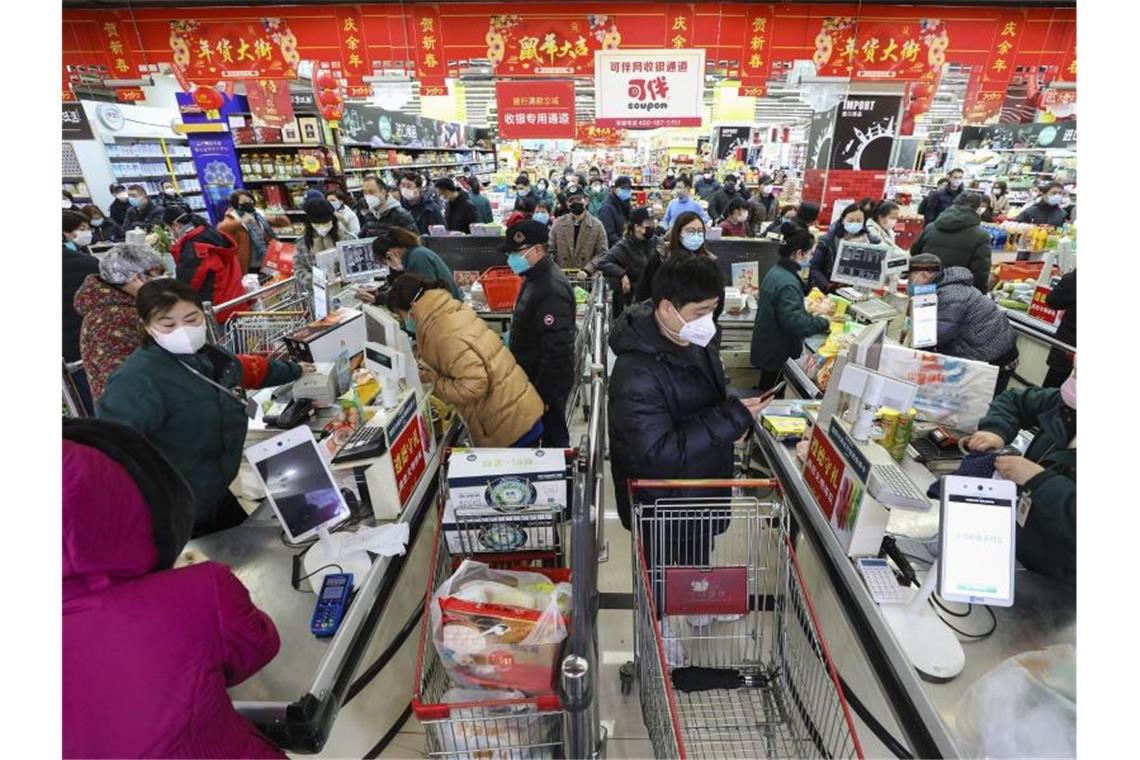 Zahl der Virus-Toten steigt - China verschärft Maßnahmen Menschen in Wuhan tragen beim Einkaufen Mundschutz-Masken. Foto: Uncredited/CHINATOPIX/AP/dpa