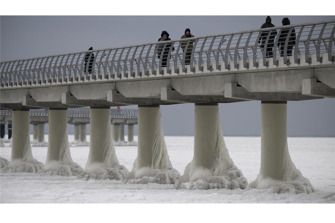 Menschen laufen am 4. Februar auf der eingefrorenen Seebrücke in Prerow. Die längste Seebrücke an der Ostseeküste ist komplett vom Eis umschlossen.