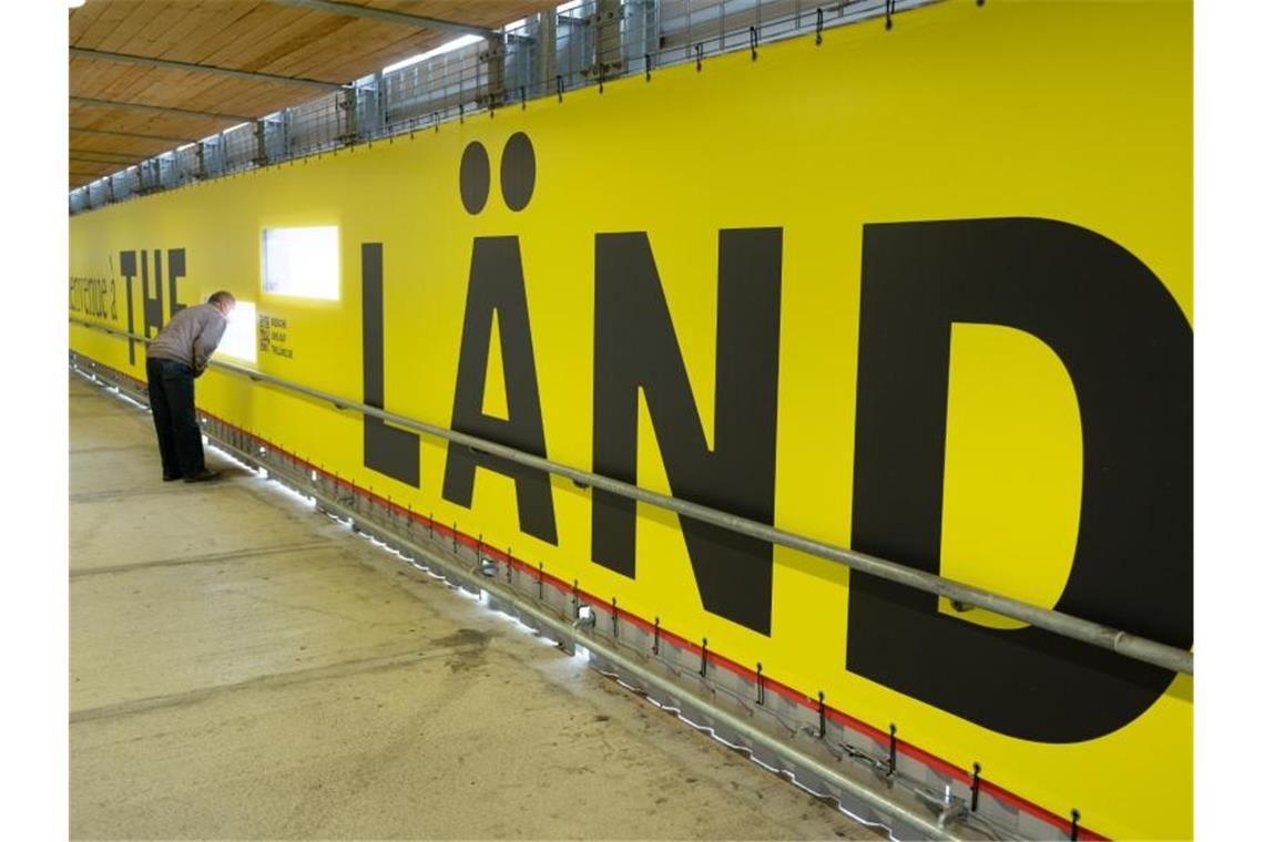 Menschen laufen an einer Werbekampagne für das Land Baden-Württemberg mit dem Titel "The Länd" vorbei. Foto: Bernd Weißbrod/dpa/Archivbild