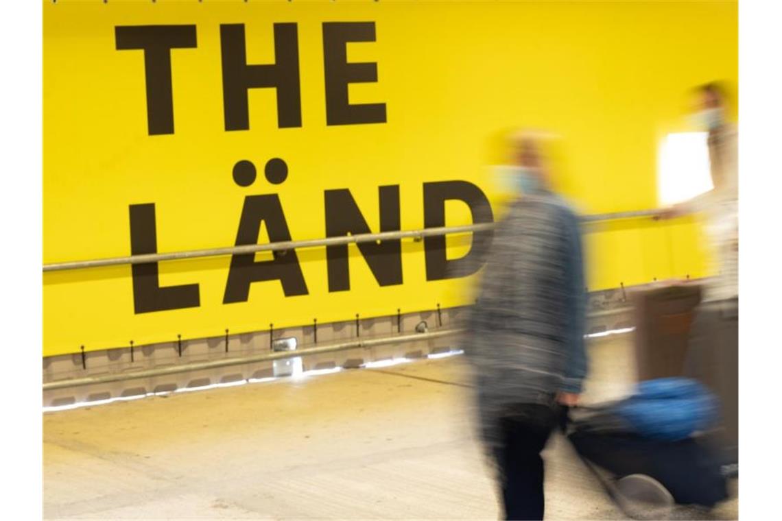 Menschen laufen im Hauptbahnhof von Stuttgart an einer Werbekampagne für das Land Baden-Württemberg vorbei. Foto: Bernd Weißbrod/dpa