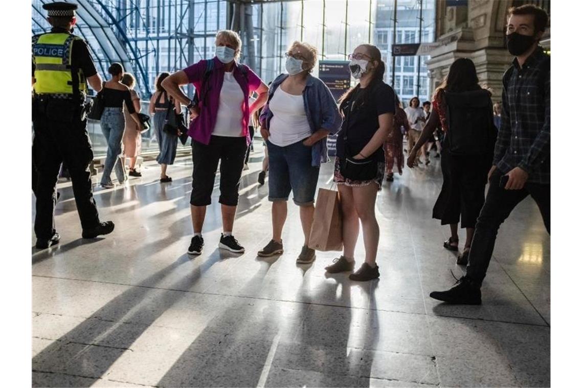 Menschen mit Mund-Nasen-Schutz stehen in einer U-Bahn Station in London. Foto: May James/SOPA Images via ZUMA Press Wire/dpa