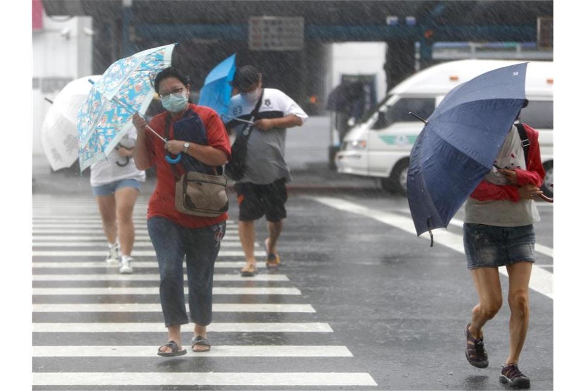 Menschen mit Regenschirmen kämpfen in Keelung gegen das Unwetter. Foto: Daniel Ceng Shou-Yi/ZUMA/dpa