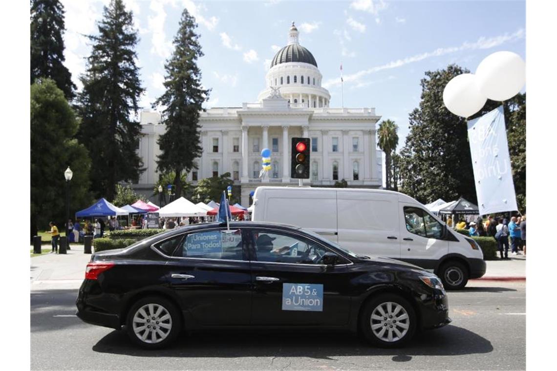 Uber und Lyft bereiten Stopp in Kalifornien vor Menschen nehmen vor dem "California State Capitol" in Sacramento an einer Demonstration zu dem Status der Fahrer auf Plattformen der Fahrdienst-Vermittler Uber und Lyft. Foto: Rich Pedroncelli/AP/dpa
