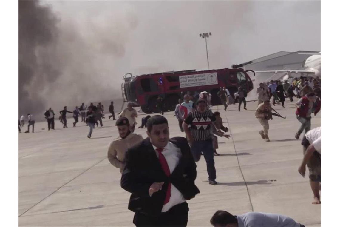 Menschen rennen nach einer schweren Explosion über den Flughafen Aden. Foto: --/AP/dpa