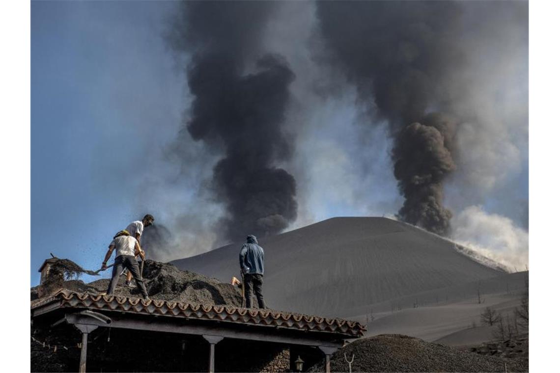 Lava ergießt sich wie ein „Tsunami“ auf La Palma Menschen säubern ein Haus von der Asche des Vulkans in Las Manchas auf der Kanareninsel La Palma. Foto: Saul Santos/AP/dpa