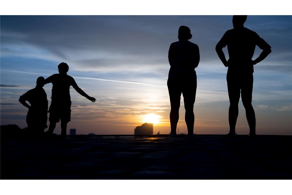 Menschen schauen sich am frühen Morgen den Sonnenaufgang auf dem Olympiaberg an.