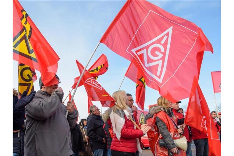 Menschen schwenken IG Metall-Flaggen. Foto: Oliver Dietze/dpa/Archivbild