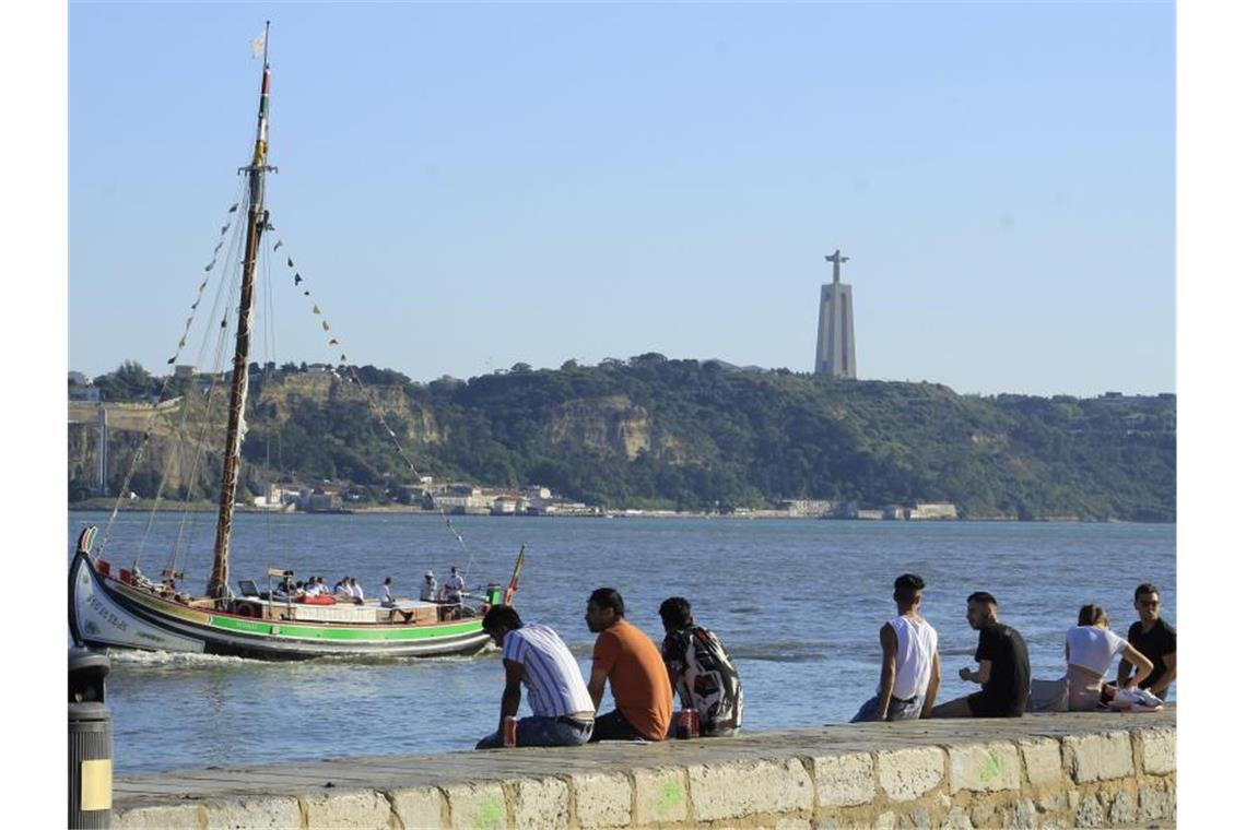 Menschen sitzen an der Küste in Cais do Sodre in Lissabon. Foto: Edson De Souza/TheNEWS2/ZUMA Wire/dpa