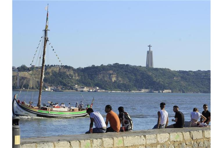 Menschen sitzen an der Küste in Cais do Sodre in Lissabon. Foto: Edson De Souza/TheNEWS2/ZUMA Wire/dpa