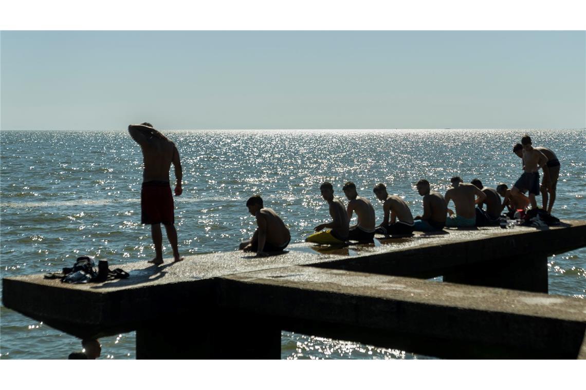 Menschen sitzen auf einem Dock in Montevideo.