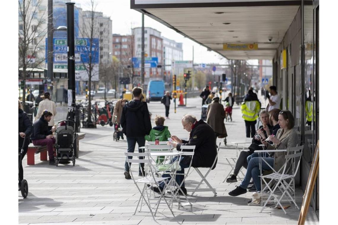 Verrückt oder genial? - Die Schweden und ihr Corona-Weg Menschen sitzen im Stadtzentrum von Stockholm vor einem Eiscafe. Foto: Ali Lorestani/TT News Agency/AP/dpa
