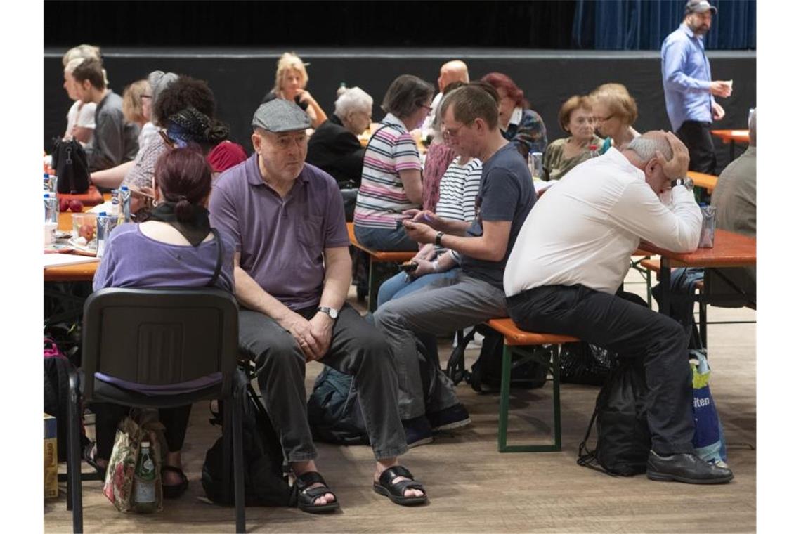 Menschen sitzen in der Sammelstelle des Roten Kreuzes außerhalb der Evakuierungszone. Foto: Boris Roessler