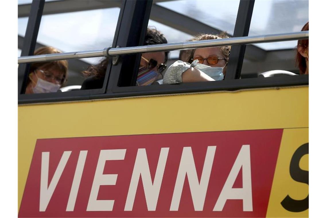 Menschen sitzen in einem Touristenbus und tragen Gesichtsmasken. 3600 der aktuell rund 6600 aktiven Fälle in Österreich werden aus Wien gemeldet.. Foto: Ronald Zak/AP/dpa
