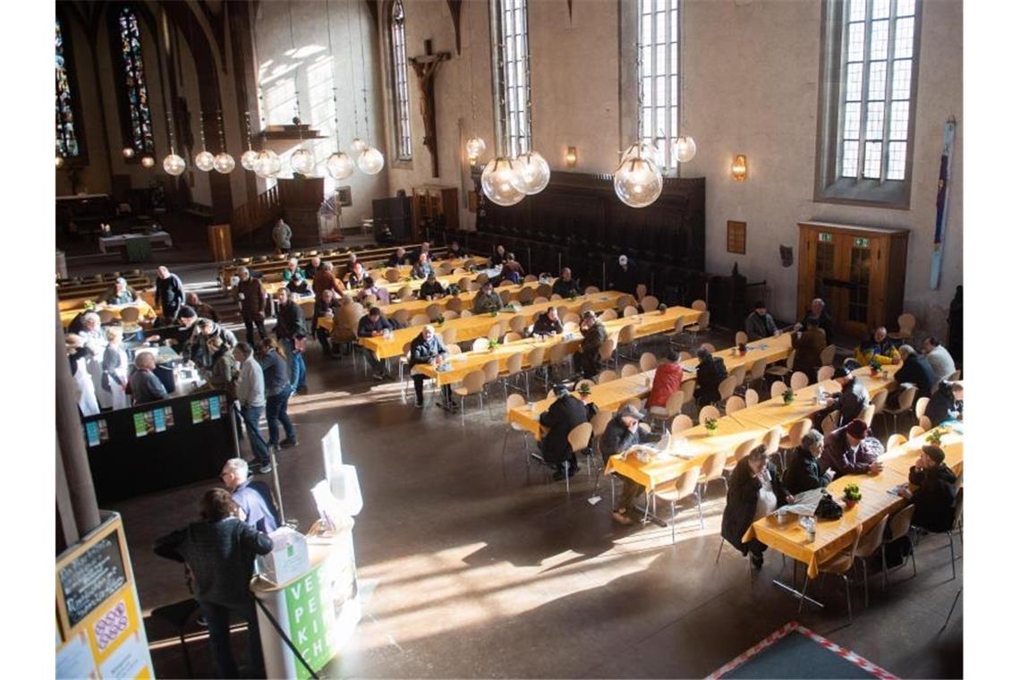 Erste Vesperkirchen öffnen: Verändertes Angebot Menschen sitzen in einer Vesperkirche in Stuttgart zusammen. Foto: Tom Weller/dpa/Archivbild