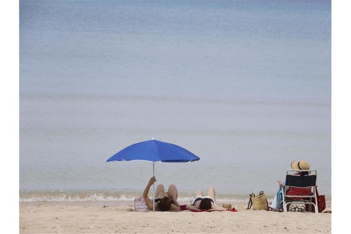 Menschen sonnen sich am Strand von Arenal auf Mallorca. Bislang dürfen aber noch keine ausländischen Touristen nach Spanien. Foto: Clara Margais/dpa