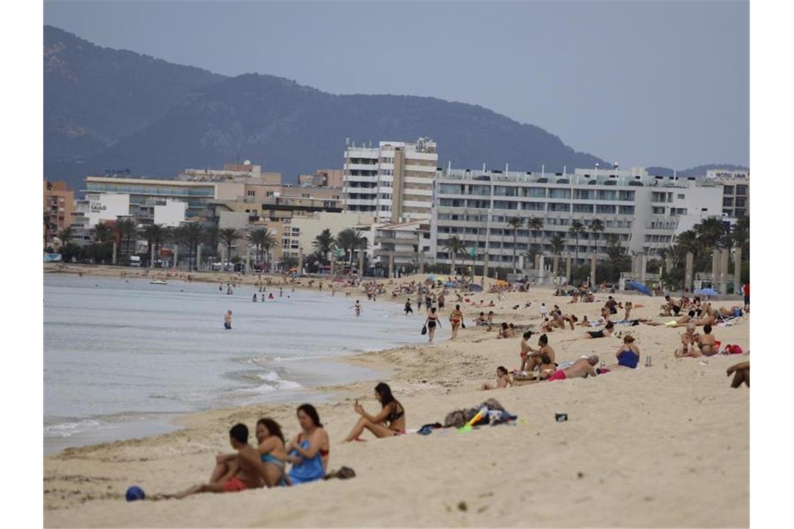 Menschen sonnen sich am Strand von Arenal auf Mallorca. Noch vor den Sommerferien soll die Reisefreiheit in der EU weitgehend zurückkehren. Foto: Clara Margais/dpa