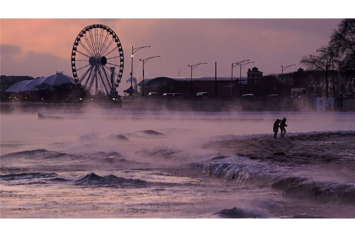 Menschen spazieren in Chicago über einen mit Eis bedeckten Strand am Ufer des Michigansees.
