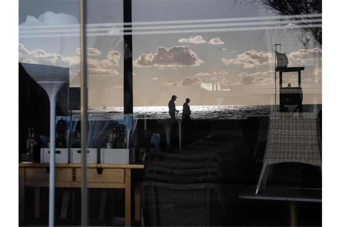 Menschen spiegeln sich im Fenster einer geschlossenen Bar in der Schinkenstraße auf Palma. Foto: Clara Margais/dpa